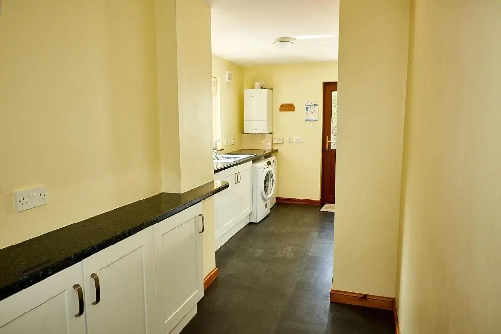 a kitchen with white cabinets and a black counter top at Rowans Inverness in Inverness