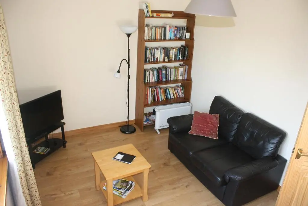 a living room with a black leather couch and a book shelf at Inver bay apartment in Tain