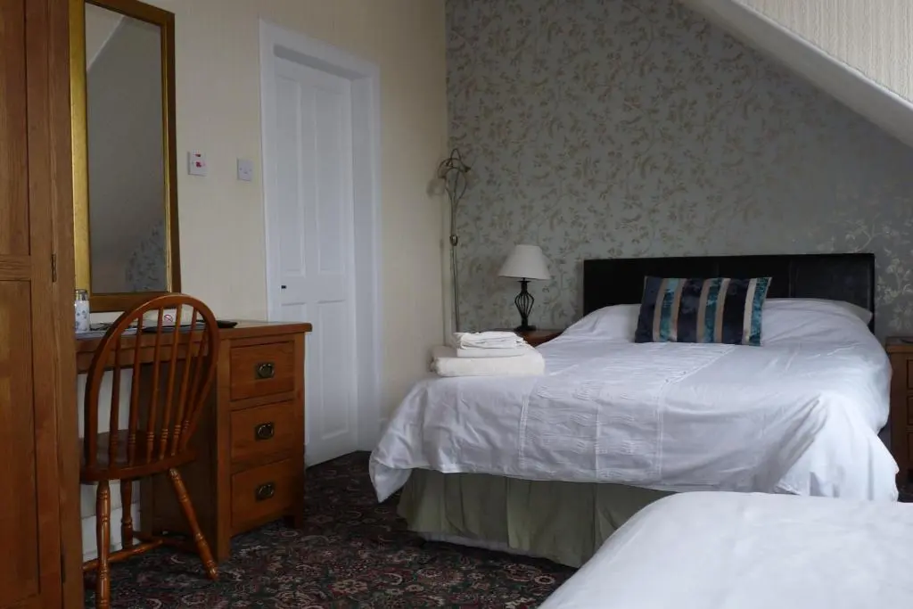 a bedroom with two beds and a dresser and a mirror at Bank Guest House in Wick