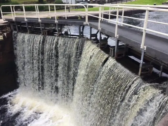 a large waterfall next to a road and a bridge at Lovat Loch Ness Apartment with private roof terrace in Fort Augustus
