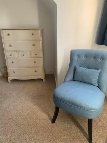 a blue chair with a pillow sitting next to a dresser at Hector's House in Aviemore