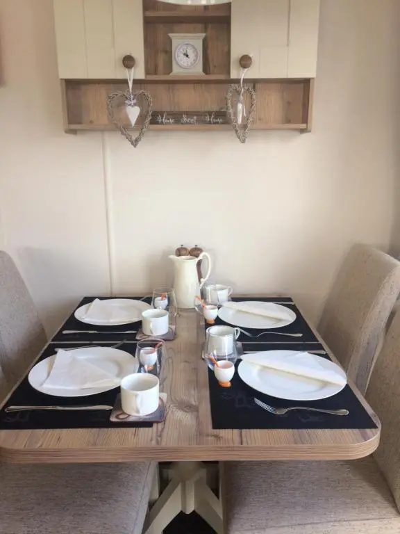 a wooden table with plates and cups on it at Cragganmore Lodge in Aviemore