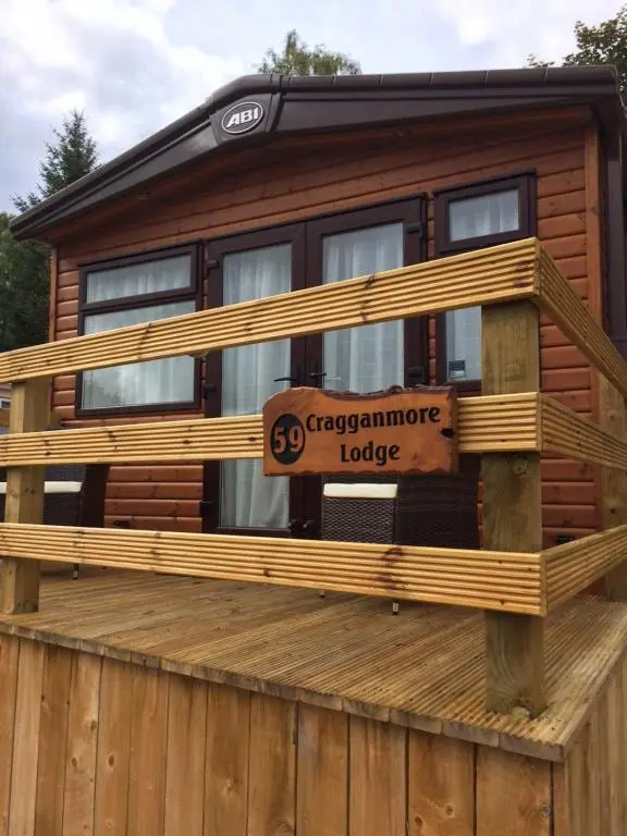 a log cabin with a sign on a deck at Cragganmore Lodge in Aviemore