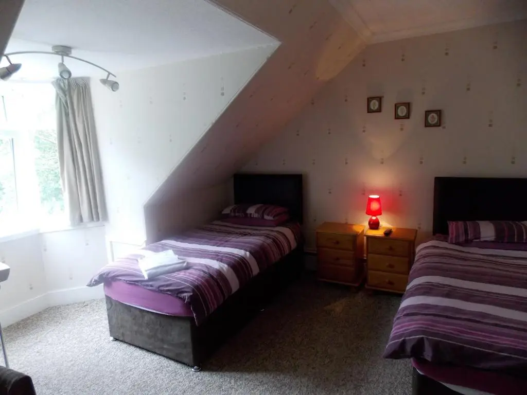 a attic bedroom with two beds and a lamp at Station View Guest House in Dyce