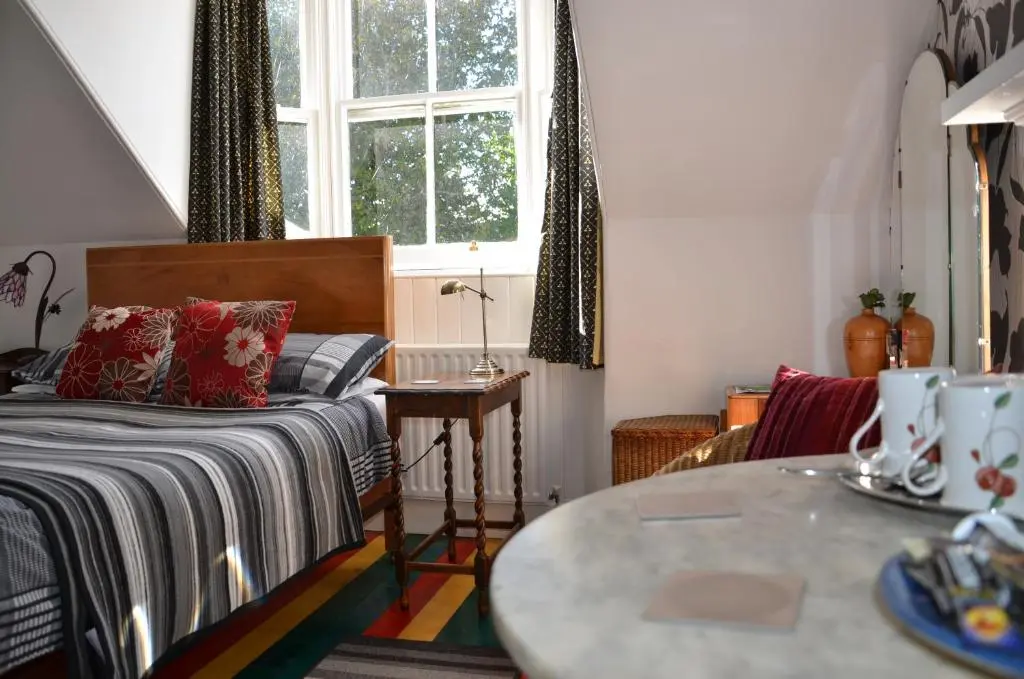 a bedroom with a bed and a table and a window at Averon House in Inverness