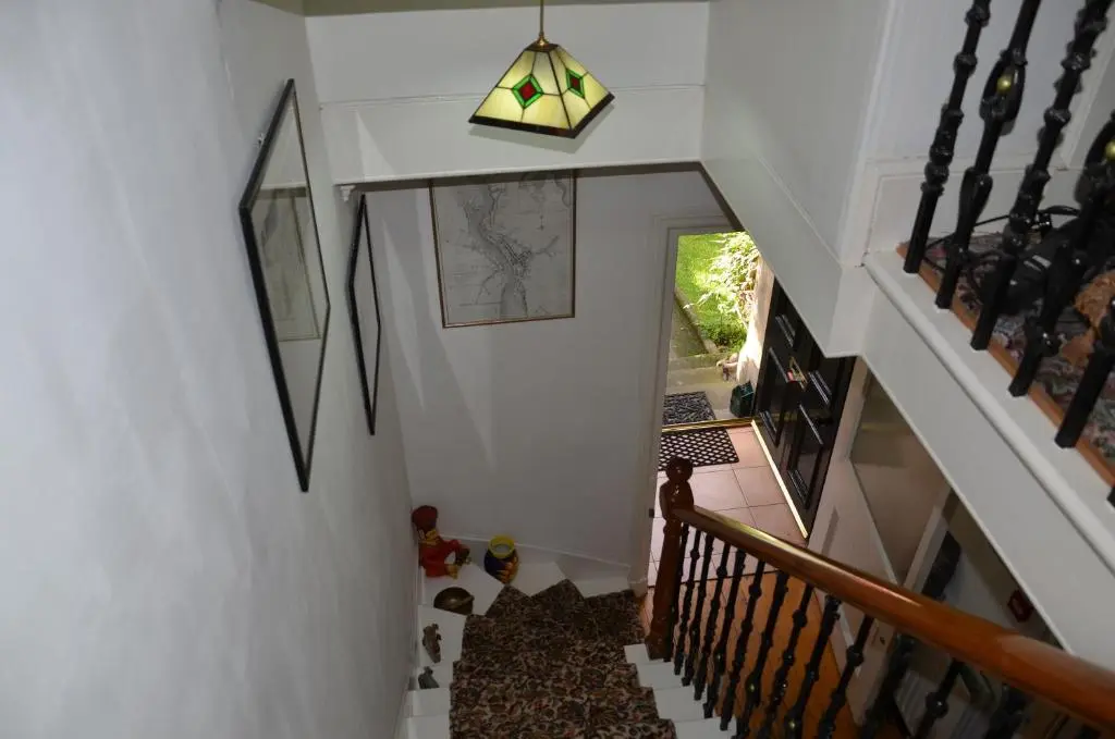 a hallway with a staircase with white walls and a light fixture at Averon House in Inverness