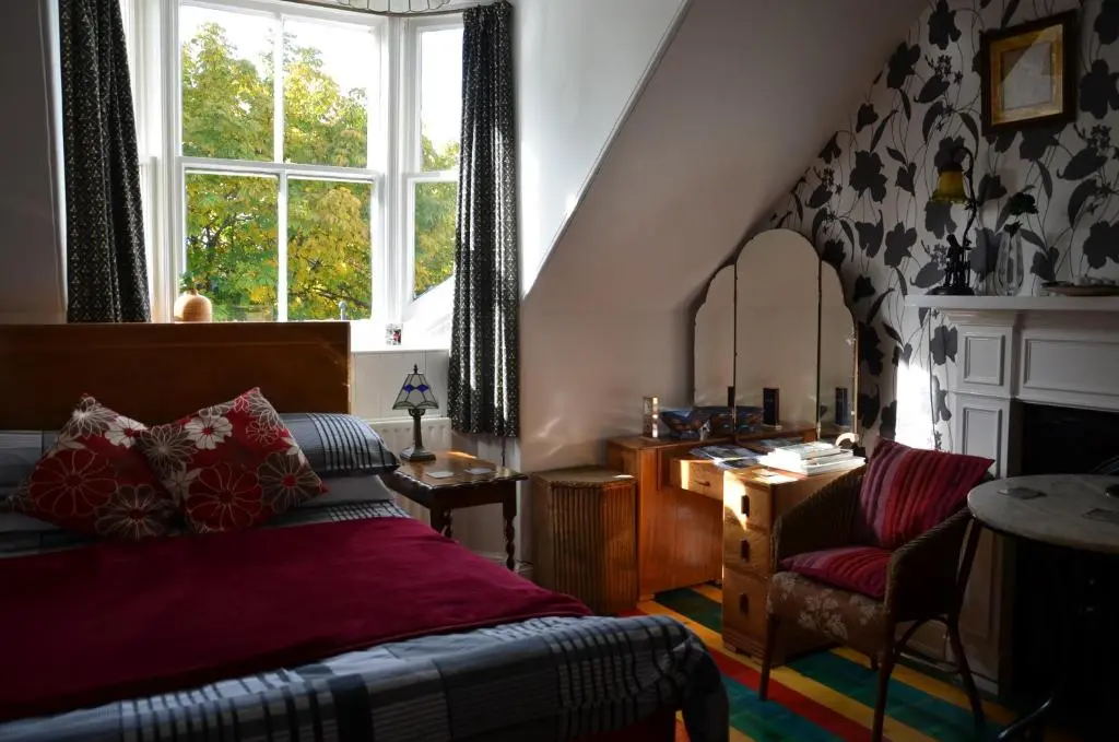 a bedroom with a bed and a desk and a window at Averon House in Inverness