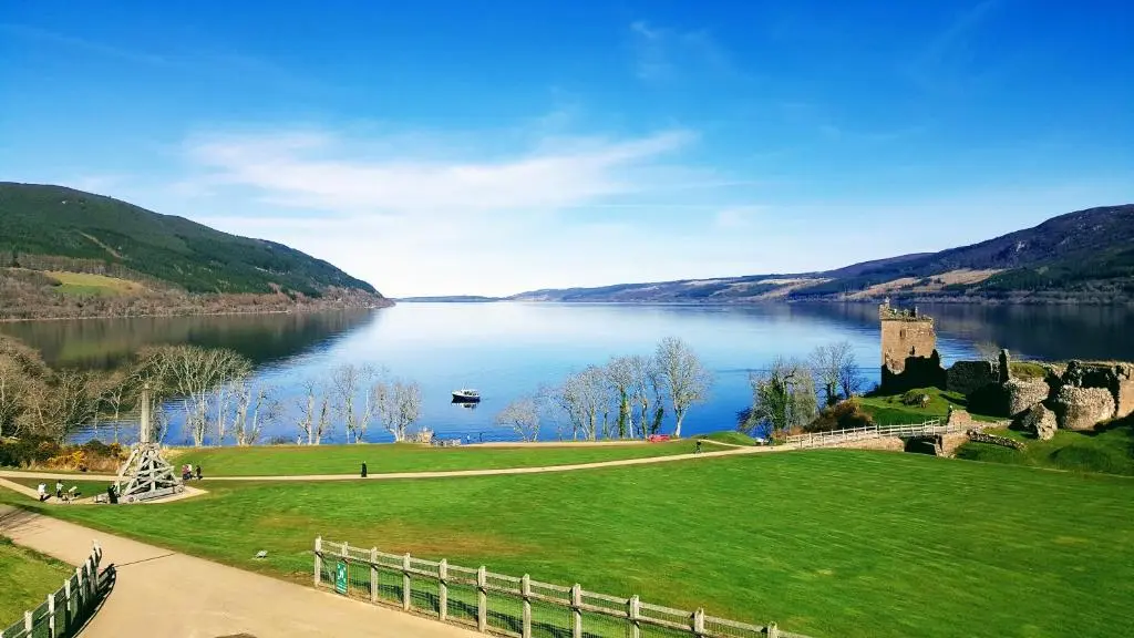 a view of a lake with a castle and a green field at Doric House in Inverness