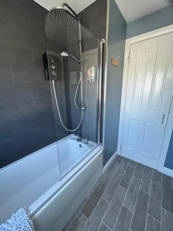 a bathroom with a tub and a shower with a glass door at No 52 - Apartment with Lounge and Dining Area - No kitchen in Ullapool