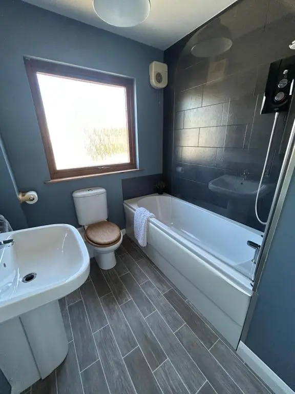 a bathroom with a tub and a toilet and a sink at No 52 - Apartment with Lounge and Dining Area - No kitchen in Ullapool