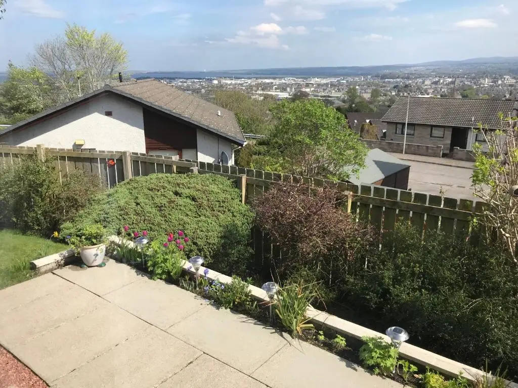 a house with a garden with flowers and a fence at Hillside View, Inverness in Inverness