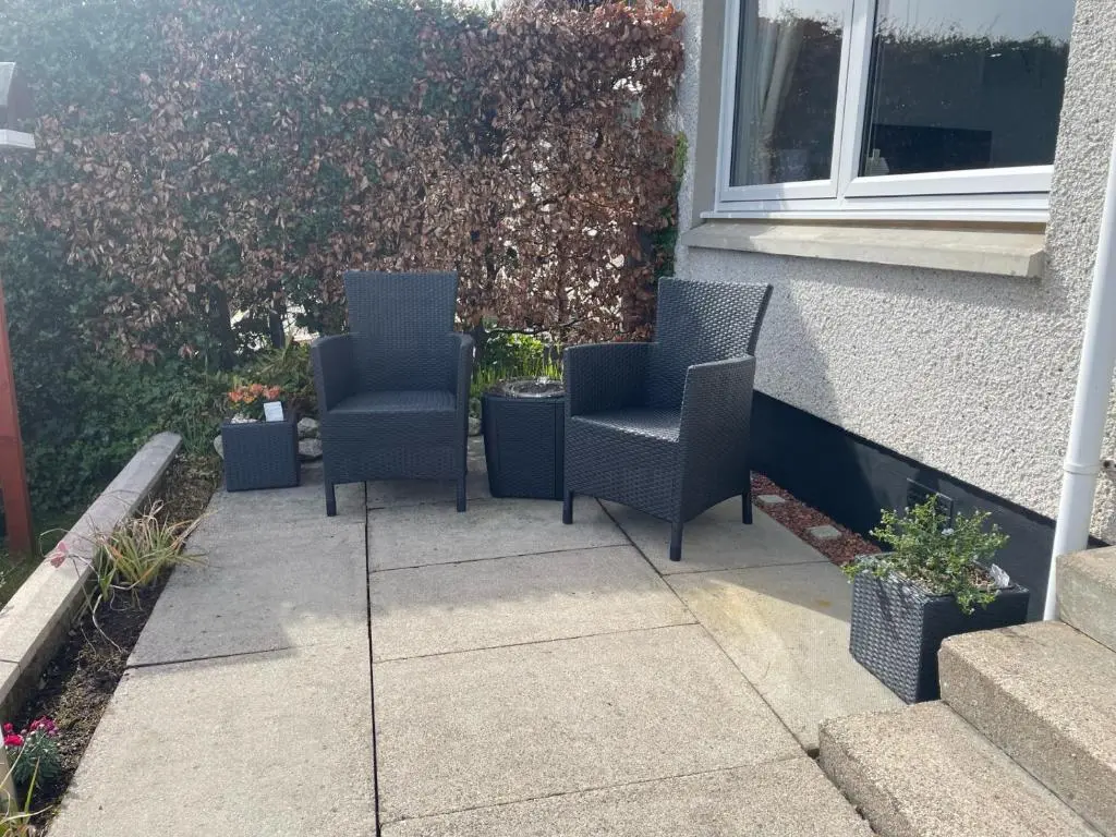 two chairs sitting on a patio next to a building at Hillside View, Inverness in Inverness