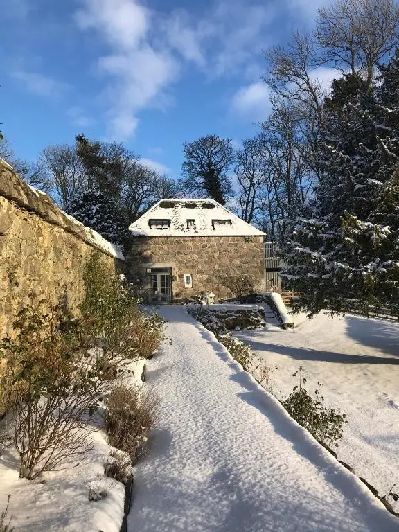 a stone house in the snow with snow covered grounds at The Lodges @ Barra Castle in Inverurie