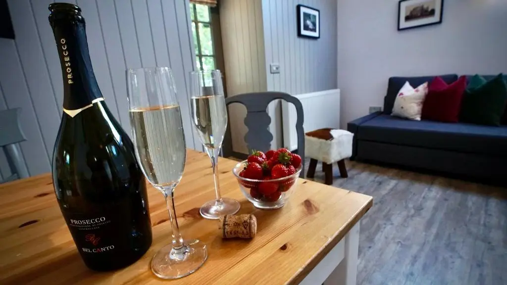 a table with two wine glasses and a bottle of wine at The Lodges @ Barra Castle in Inverurie