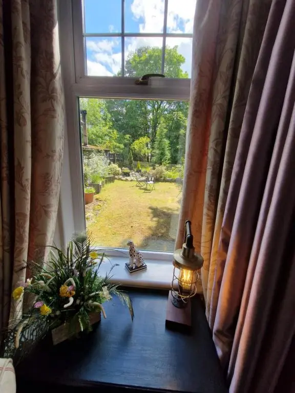 a window with a candle and flowers on a table at Eagle View Guest House in Newtonmore