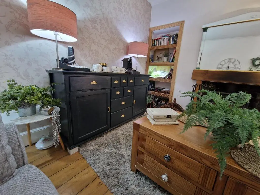 a living room with a black dresser and a mirror at Eagle View Guest House in Newtonmore
