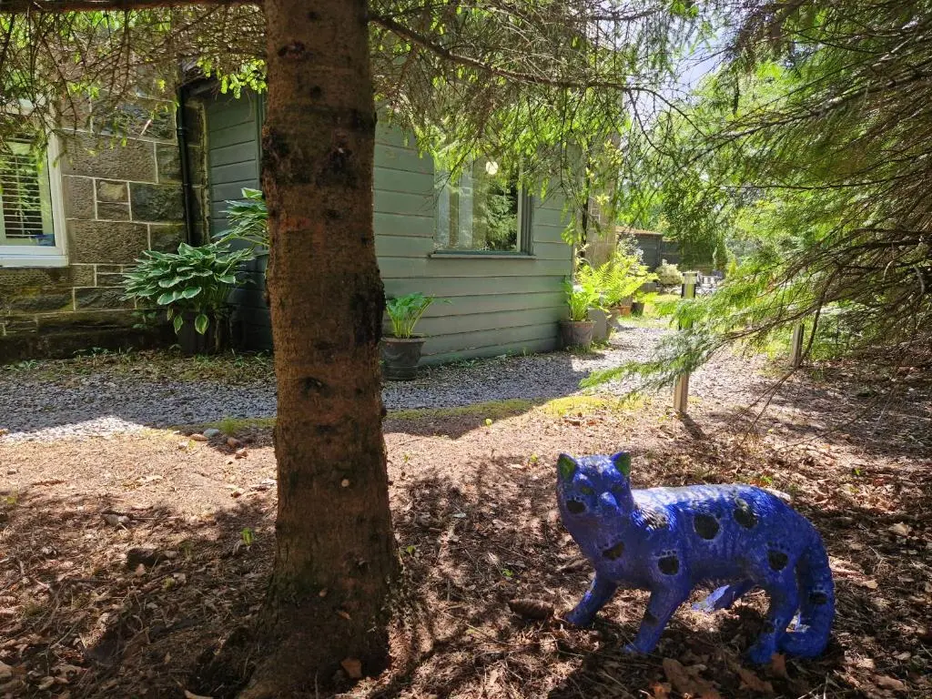 a blue cow statue sitting next to a tree at Eagle View Guest House in Newtonmore
