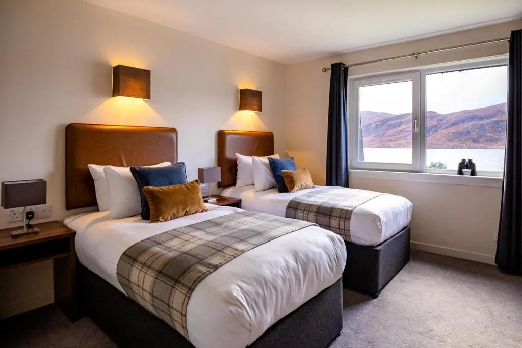 a hotel room with two beds and a window at Harbour House in Ullapool