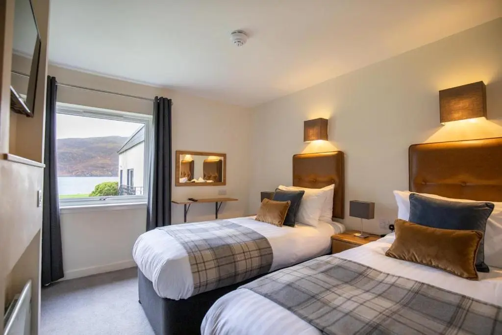 a hotel room with two beds and a window at Harbour House in Ullapool