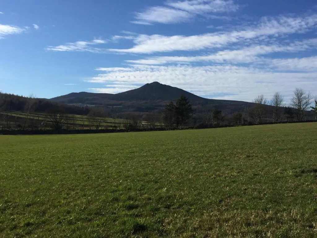 a large green field with a mountain in the background at Broadsea in Inverurie