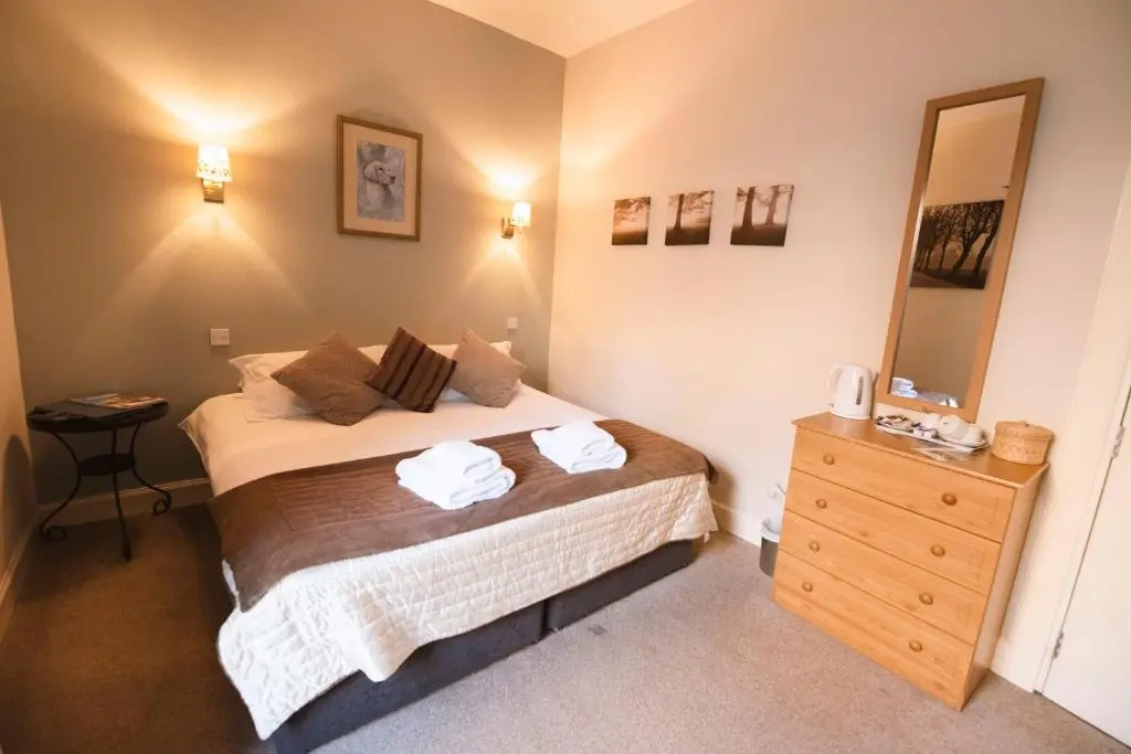 a bedroom with a bed with two towels on it at The Kirkmichael Hotel in Kirkmichael