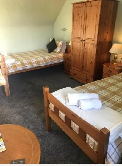 a hotel room with two beds and a table at Elgin Guest House in Elgin