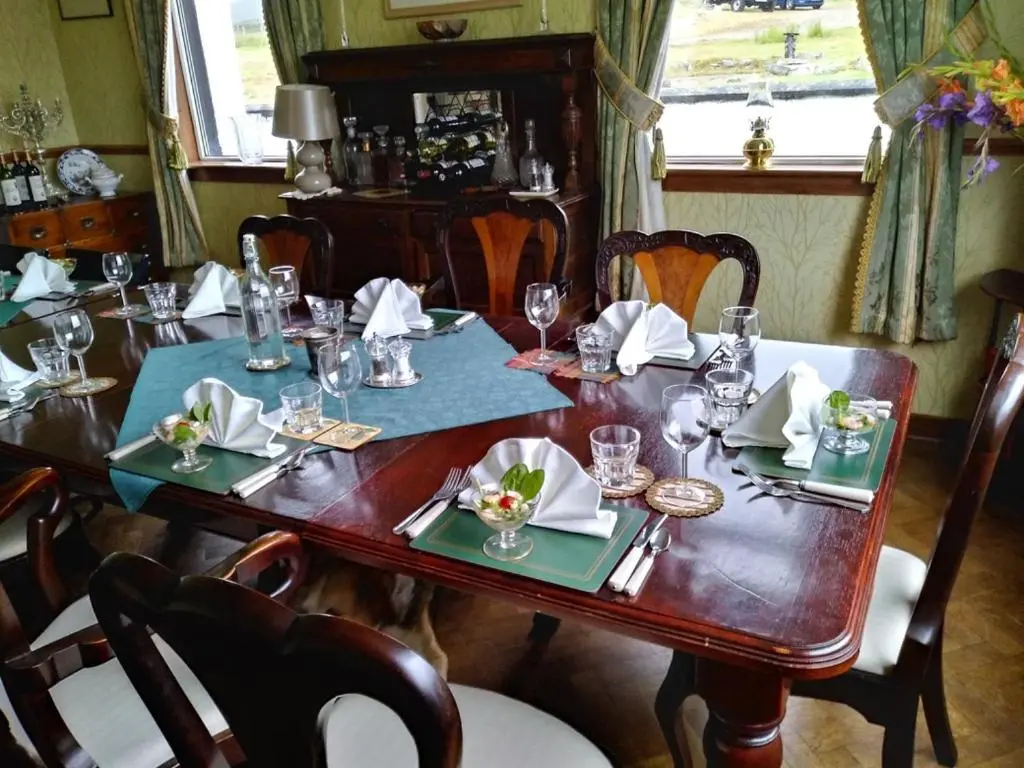 a wooden table with glasses and napkins on it at Garvault House in Kinbrace