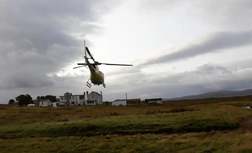 a small helicopter is flying over a field at Garvault House in Kinbrace