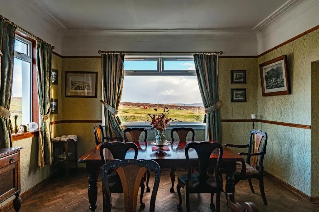 a dining room with a table and chairs and a window at Garvault House in Kinbrace