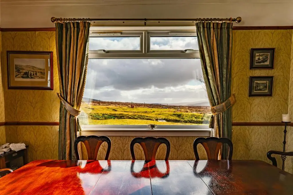 a dining room with a table and a large window at Garvault House in Kinbrace