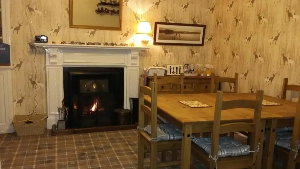a dining room with a table and a fireplace at Gowanbrae in Dufftown