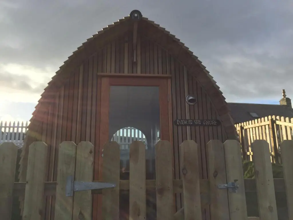 a wooden fence with a wooden door in front of a building at Door to the Shore - Seafront Cottages in Sandhaven