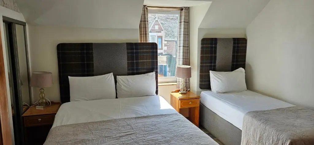 a hotel room with two beds and a window at Armadale Guest House in Inverness