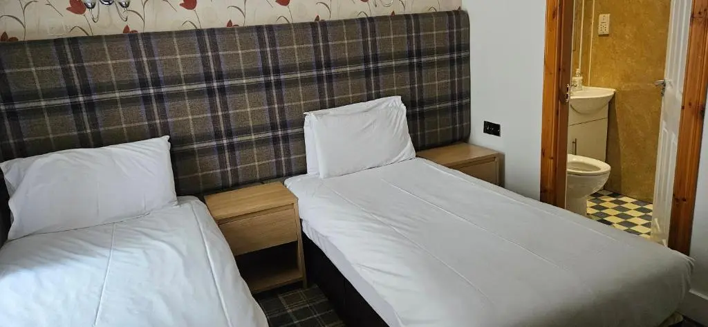 two beds in a small room with a bathroom at Armadale Guest House in Inverness