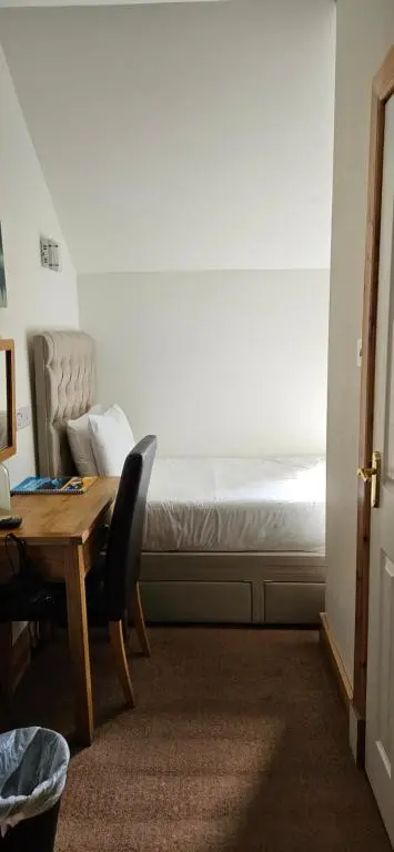a bedroom with a bed and a desk and a table at Armadale Guest House in Inverness