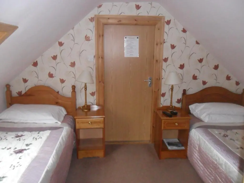 a bedroom with two beds and two lamps and a door at Armadale Guest House in Inverness