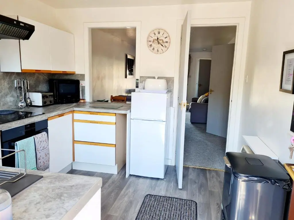 a kitchen with a refrigerator and a clock on the wall at Aviemore Stay & Explore in Aviemore