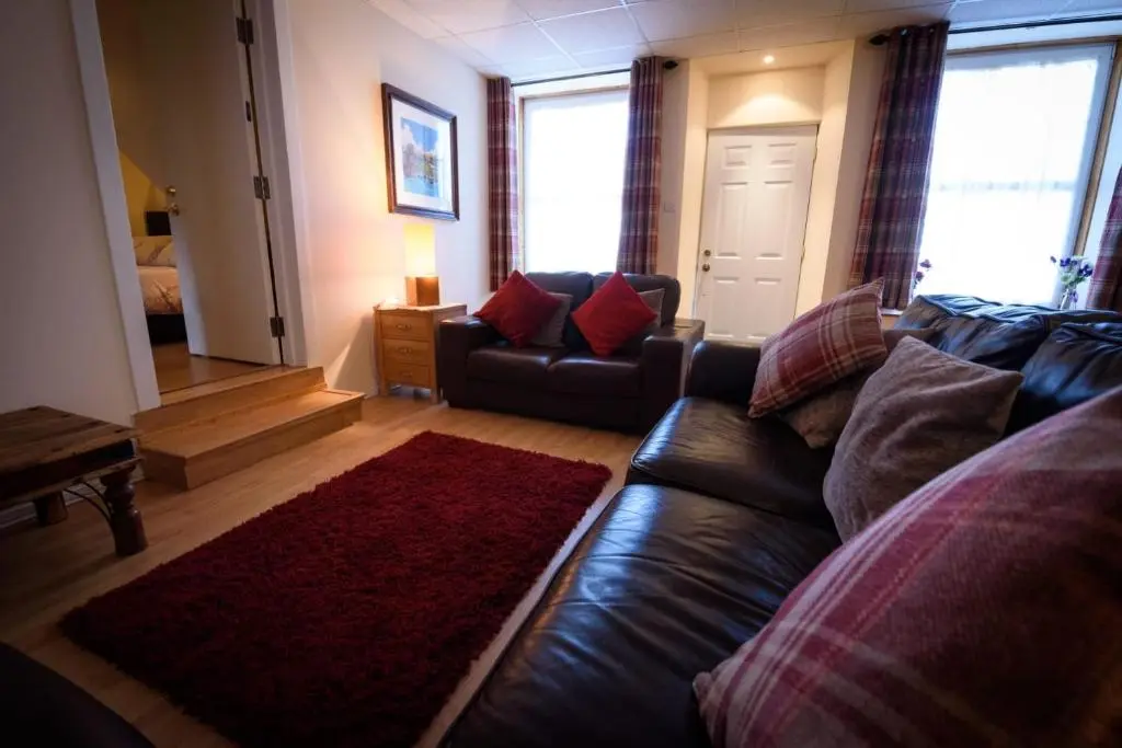 a living room with a leather couch and a red rug at The Old Chemist in Cullen