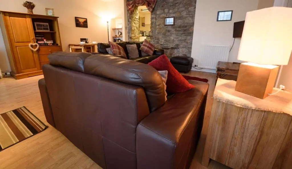 a living room with a brown leather couch and a table at The Old Chemist in Cullen