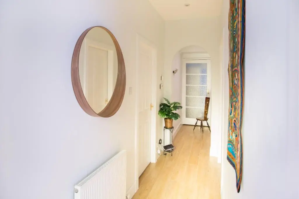 a hallway with a mirror on the wall and a table at Crown Apartment in Inverness