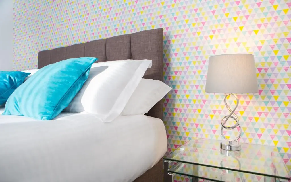 a bed with pillows and a table with a lamp at Crown Apartment in Inverness