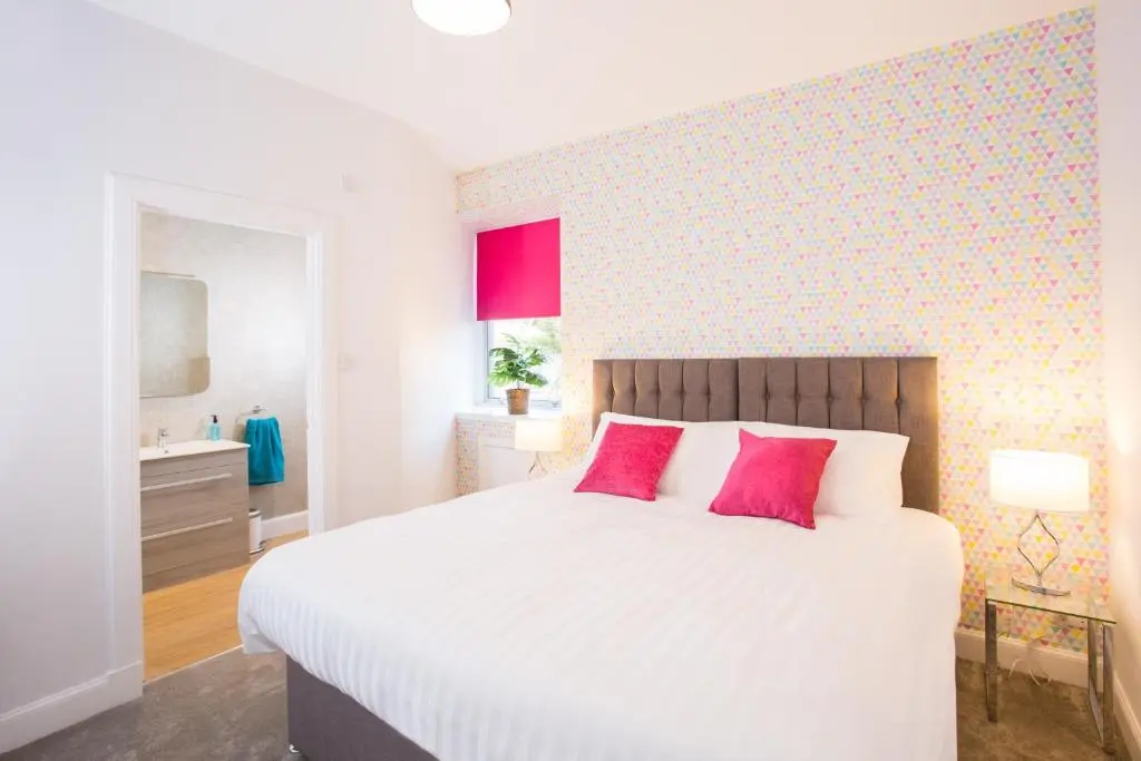 a bedroom with a large white bed with red pillows at Crown Apartment in Inverness