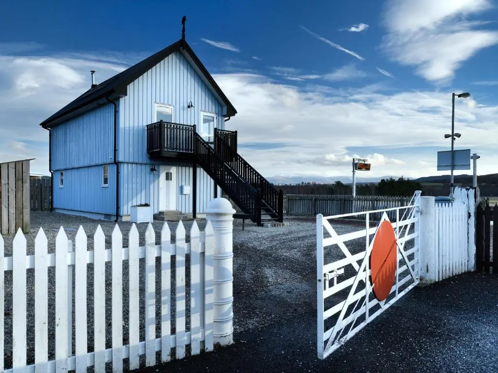 a blue building with a white fence and a gate at Signal Box in Newtonmore
