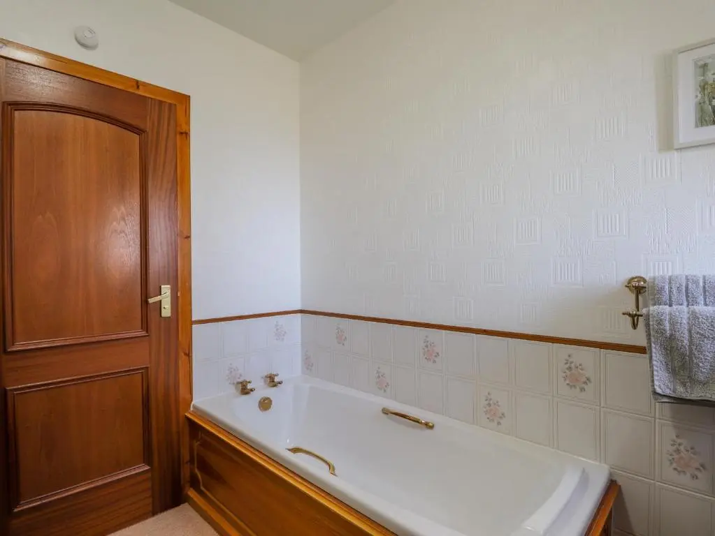 a bath tub in a bathroom with a wooden door at Braehead Croft in Portessie