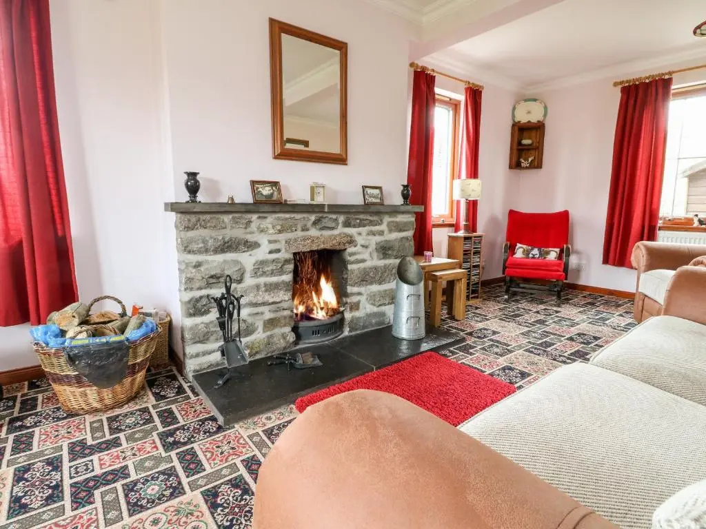 a living room with a fireplace and red curtains at Creag-na-Sanais in Laggan