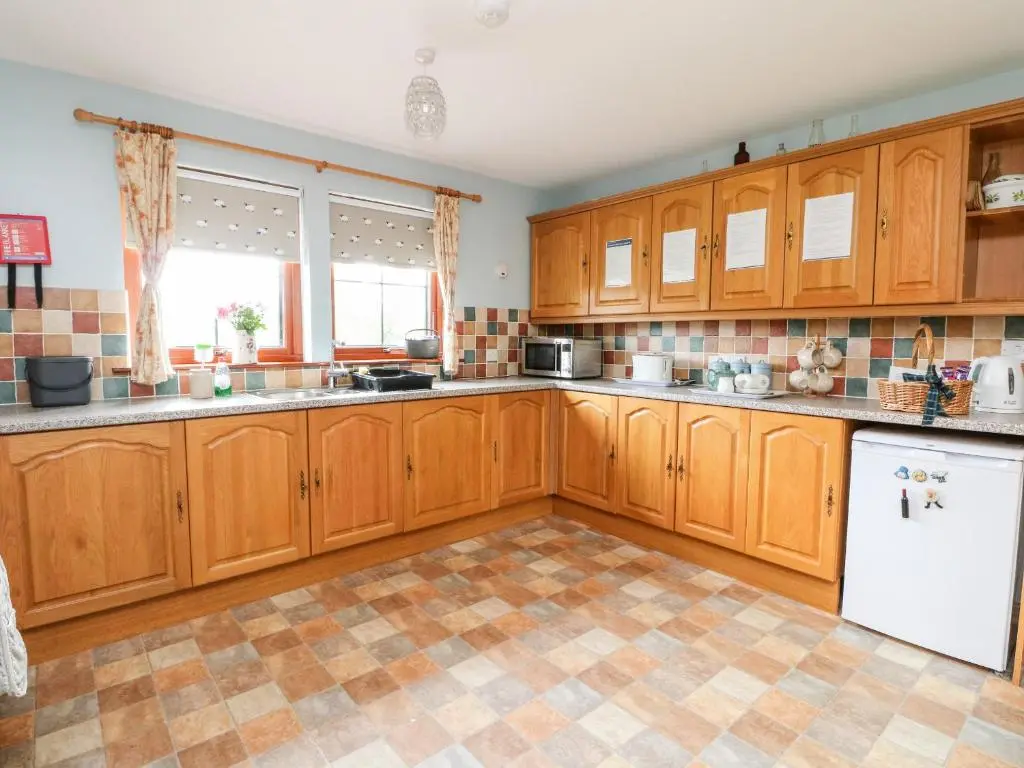 a kitchen with wooden cabinets and a tile floor at Creag-na-Sanais in Laggan