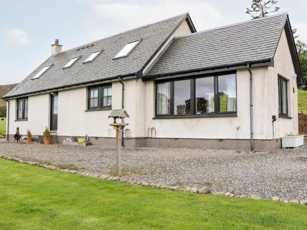 a white house with windows on a gravel driveway at Creag-na-Sanais in Laggan