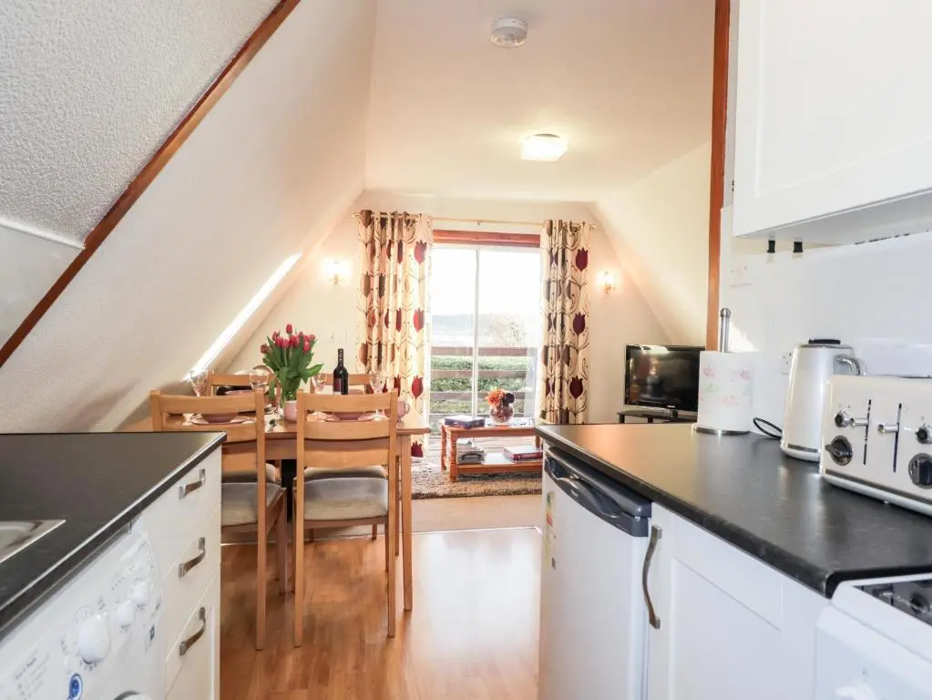 a kitchen with a table and a dining room at Larchfield Chalet 2 in Auchterneed