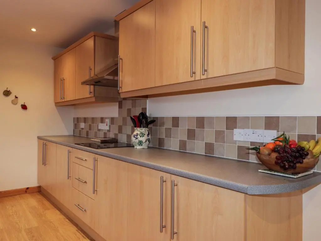a kitchen with wooden cabinets and a bowl of fruit on the counter at Bruach Gorm Cottage in Grantown on Spey