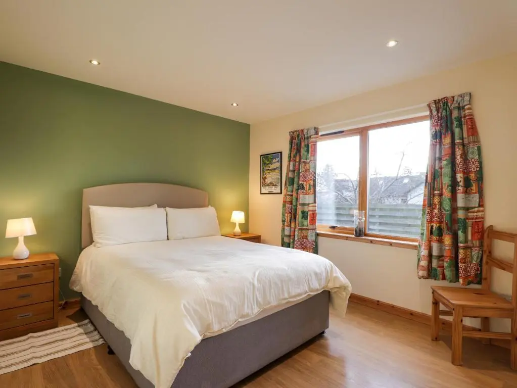 a bedroom with a large bed and a window at Bruach Gorm Cottage in Grantown on Spey